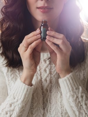 young caucasian model with long dark hair poses for the camera with hand near her face portrait of caucasian woman poses for the camera isolated on grey background